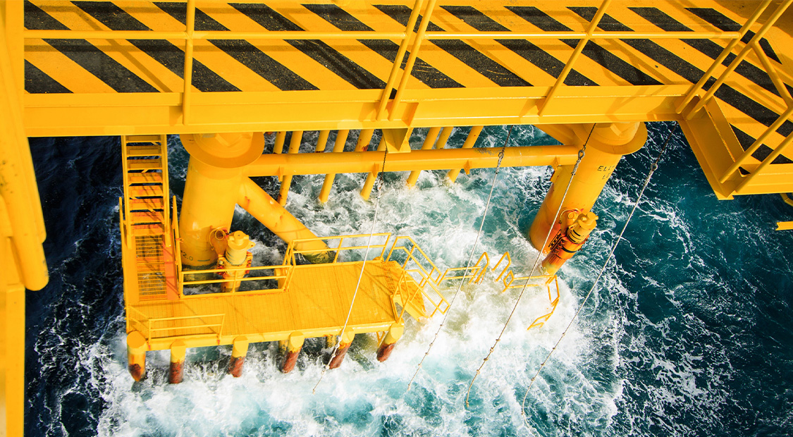Picture of an orange oil rig at sea.